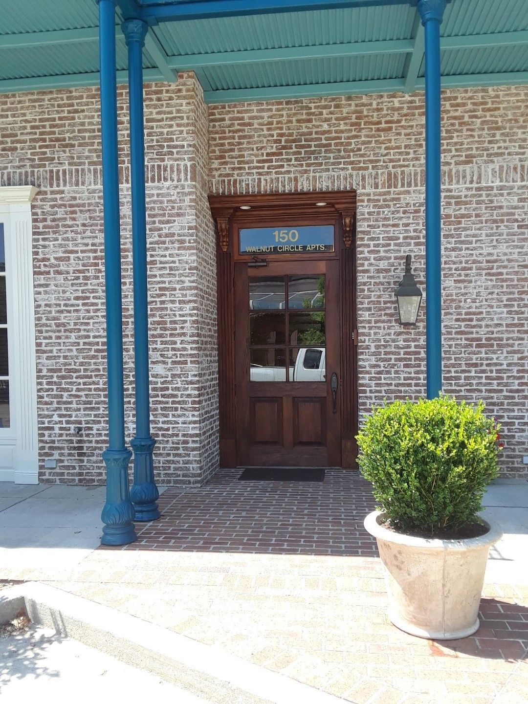A brick building with a wooden door and a potted plant in front of it