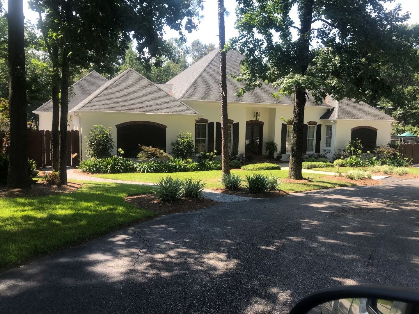 A large white house is surrounded by trees and grass