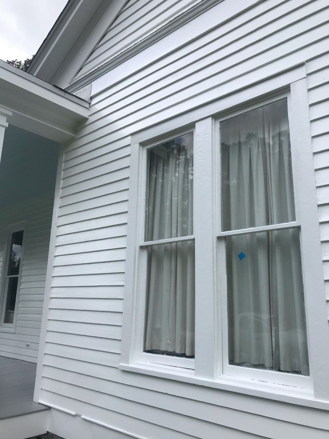 A white house with two windows and a porch.