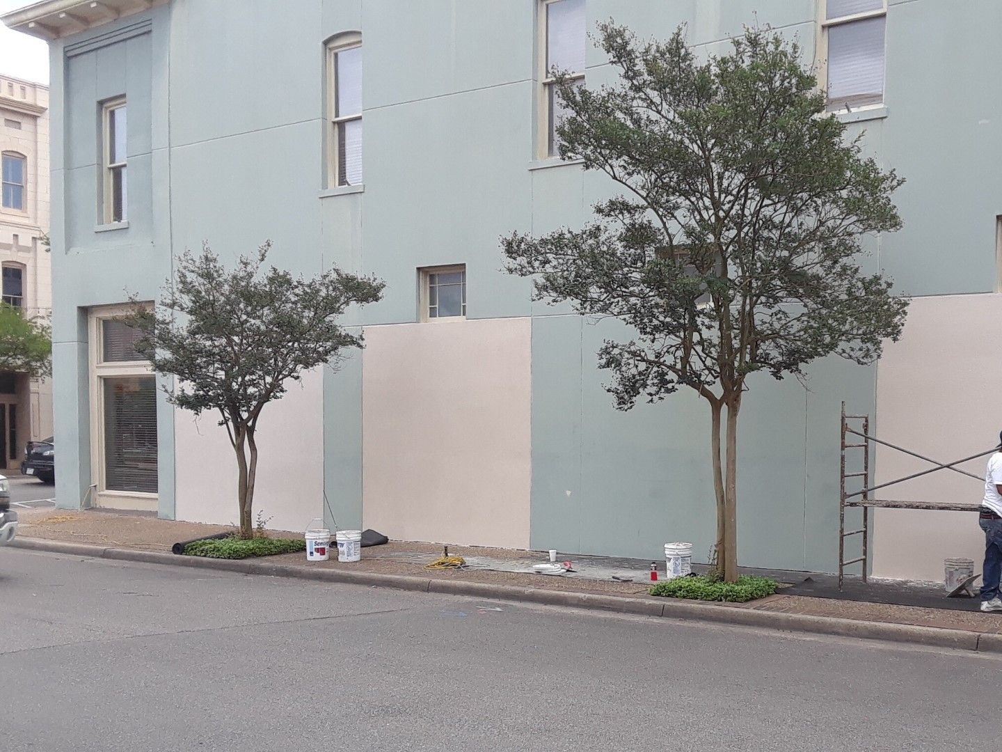 A man is standing in front of a building that is being painted