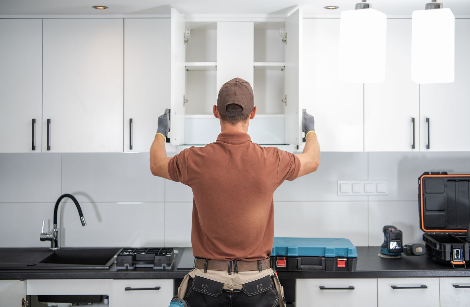 A man is installing cabinets in a kitchen.