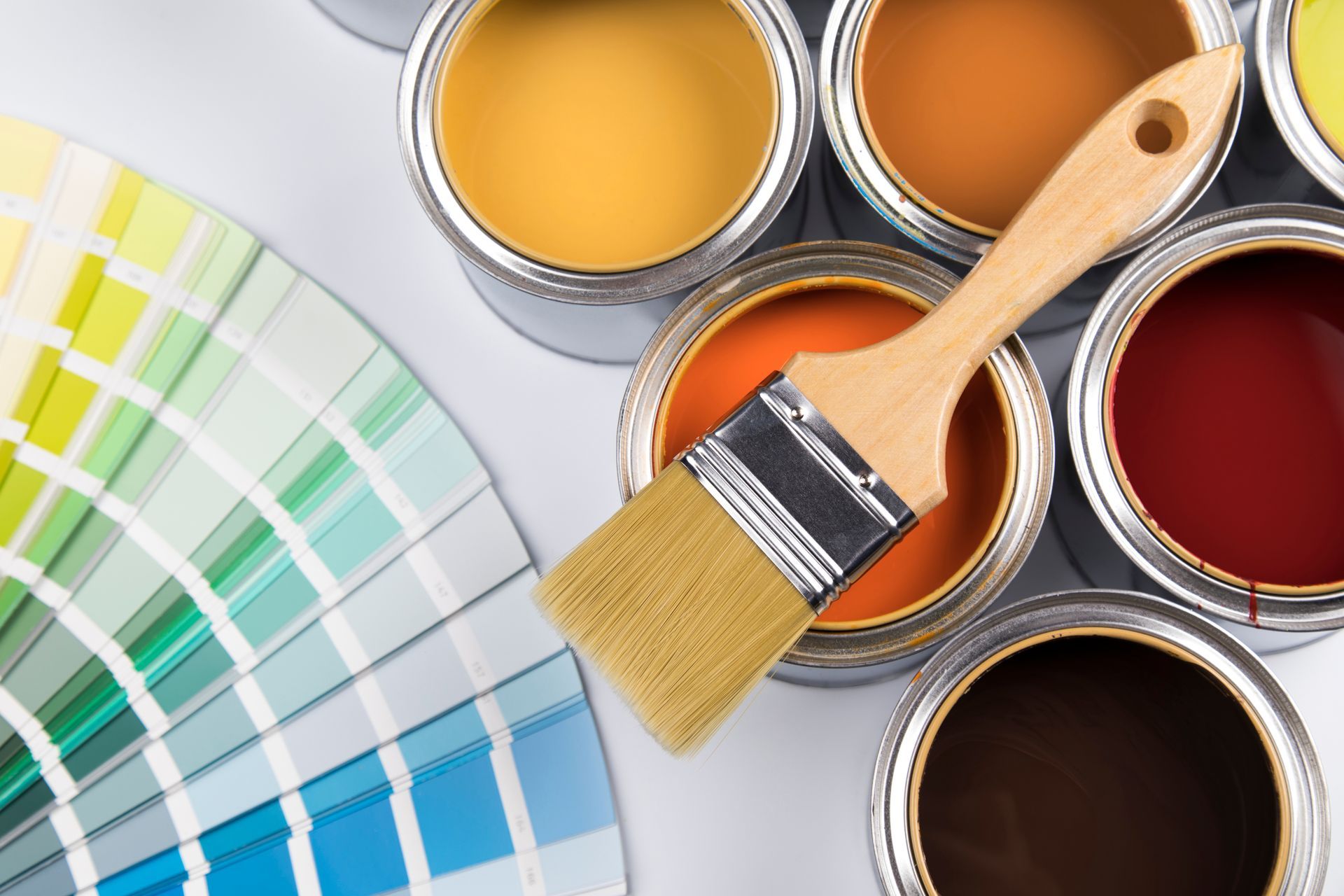 A brush is sitting on top of a bunch of paint cans.