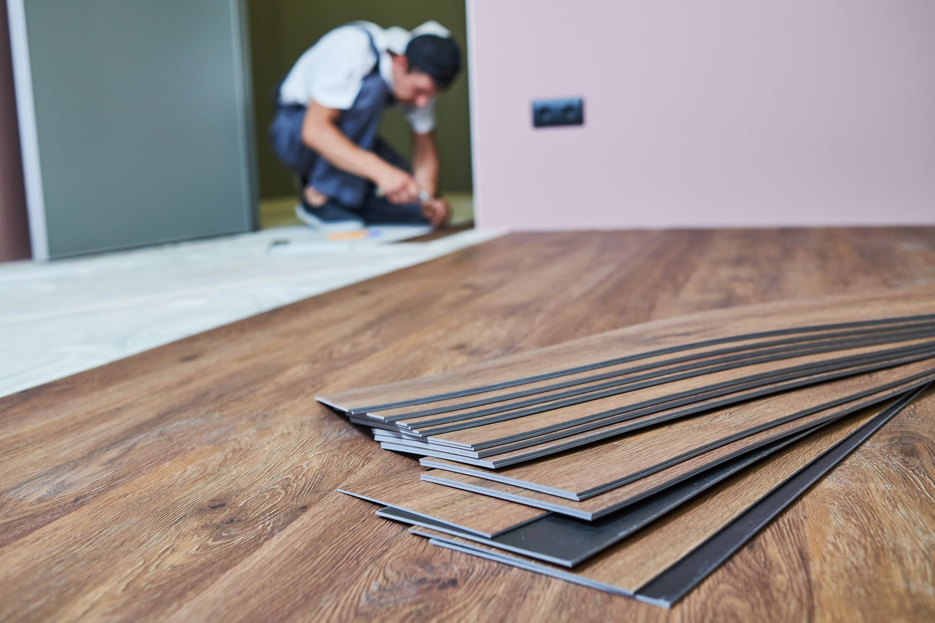 A man is installing a wooden floor in a room.
