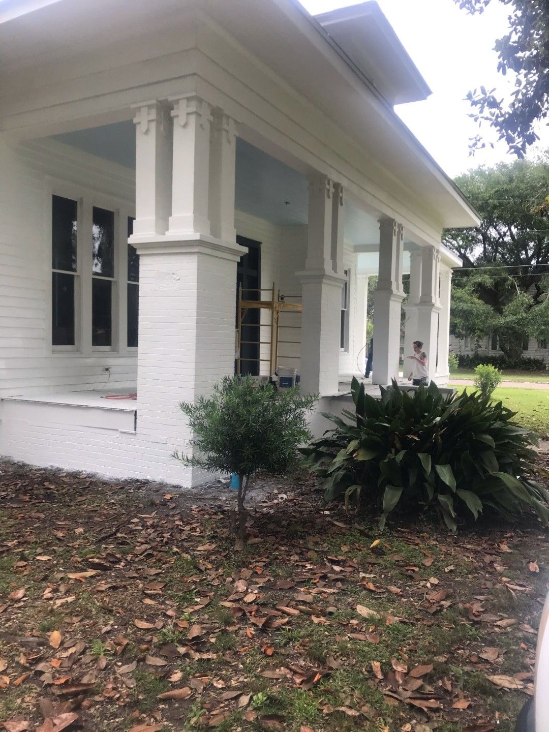 A white house with a porch is being painted