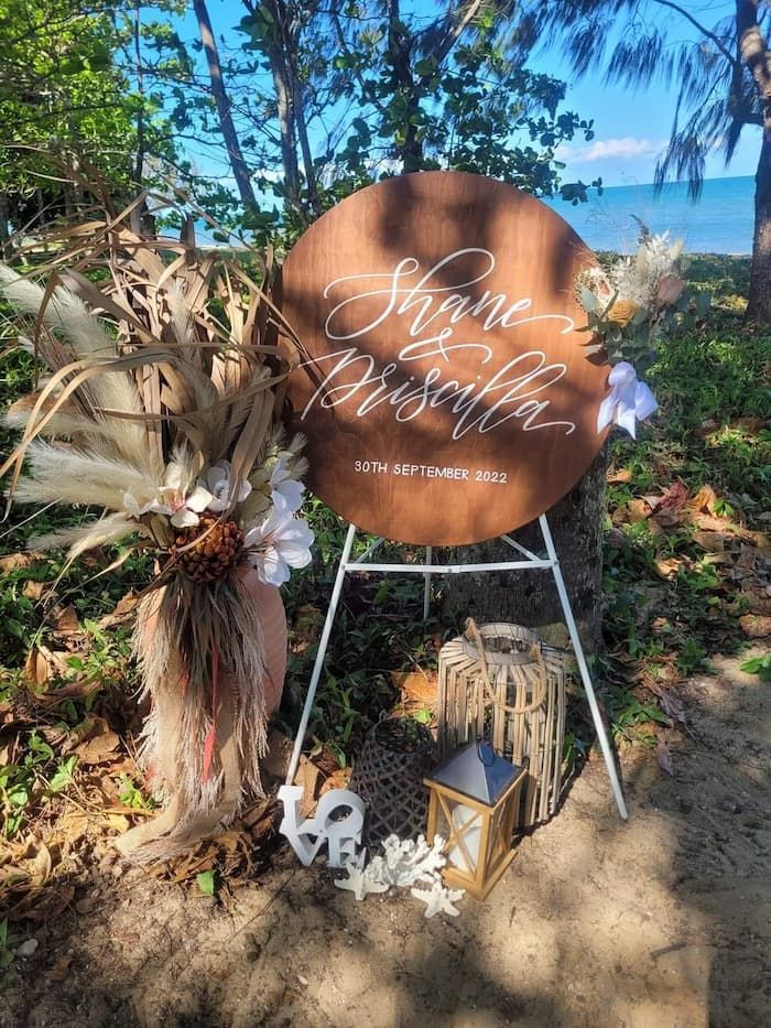 A Wooden Sign Is Sitting on Top of A Metal Stand in The Woods — Creative Events Innisfail in Mission Beach, QLD