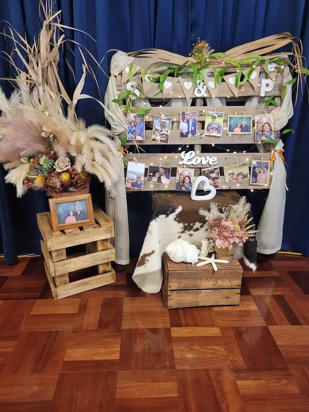 A Wooden Table with Pictures and Flowers on It Is Sitting on A Wooden Floor — Creative Events Innisfail in Mission Beach, QLD