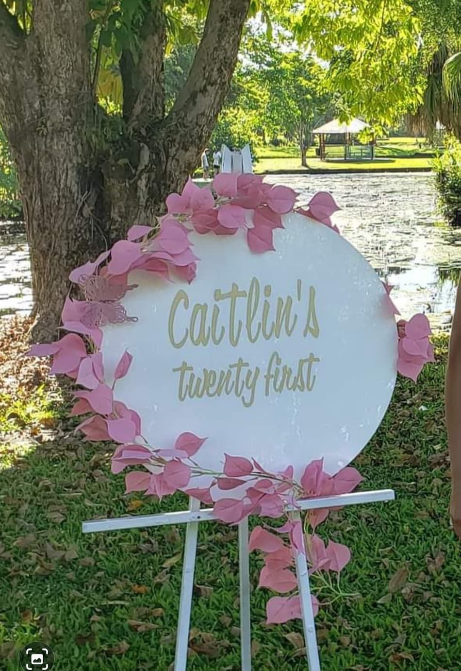A White Sign with Pink Leaves on It Is Sitting on Top of A White Easel — Creative Events Innisfail in Tully, QLD