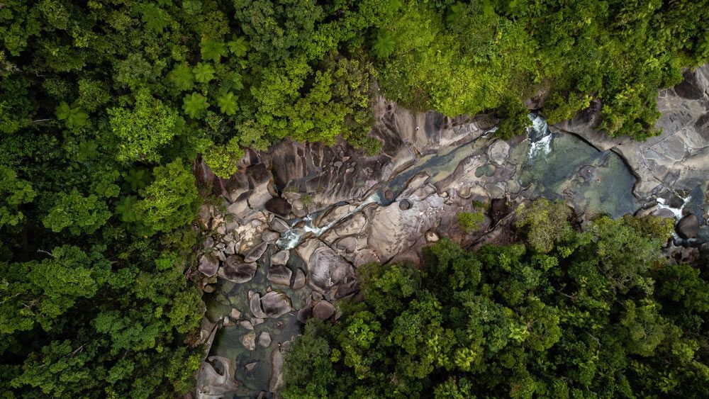 An Aerial View of A Waterfall in The Middle of A Lush Green Forest — Creative Events Innisfail in Babinda, QLD