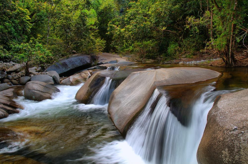 A Waterfall Is Surrounded by Rocks and Trees in The Middle of A River — Creative Events Innisfail in Babinda, QLD