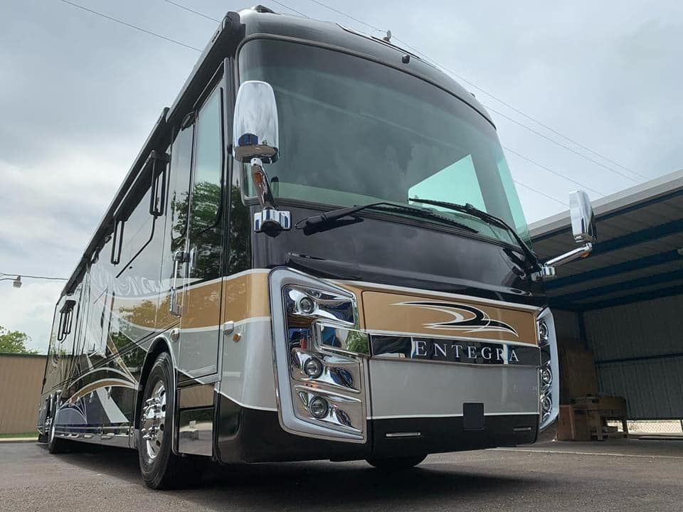 A large rv is parked in front of a building.