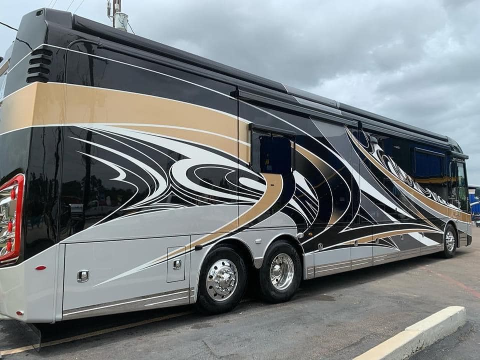 A large black and gold bus is parked in a parking lot.