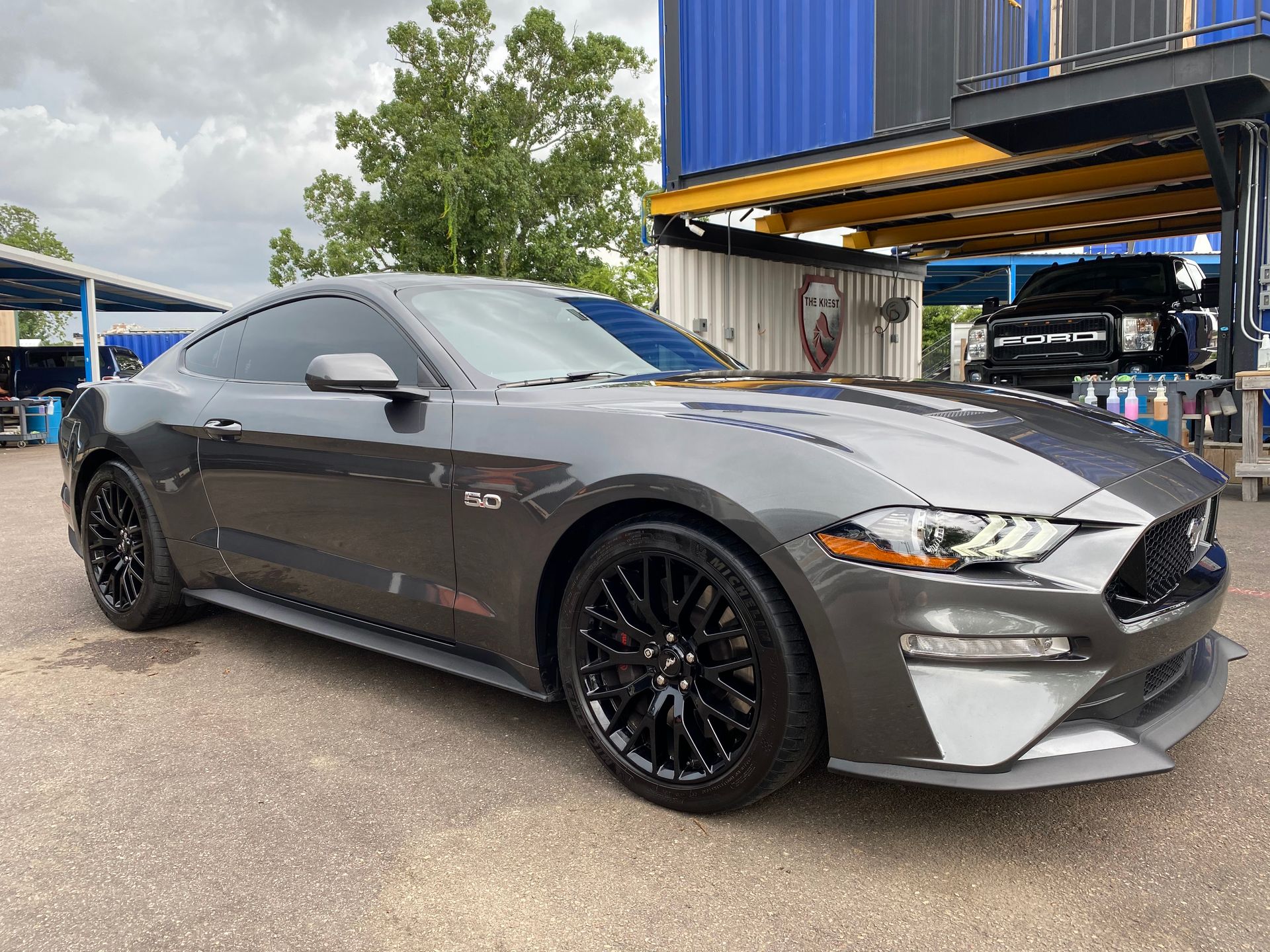 A gray ford mustang is parked in front of a building.