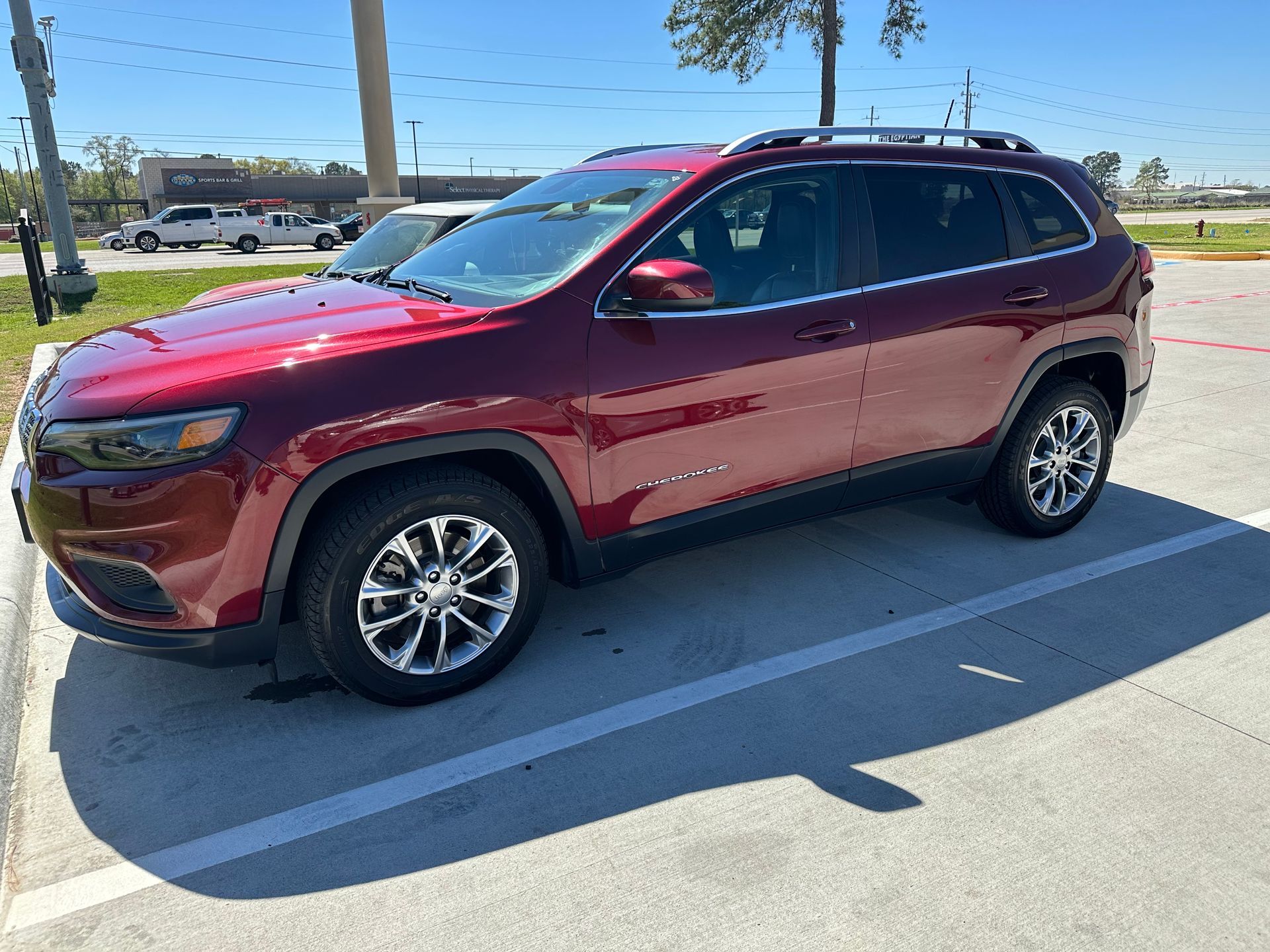 A red jeep is parked in a parking lot.