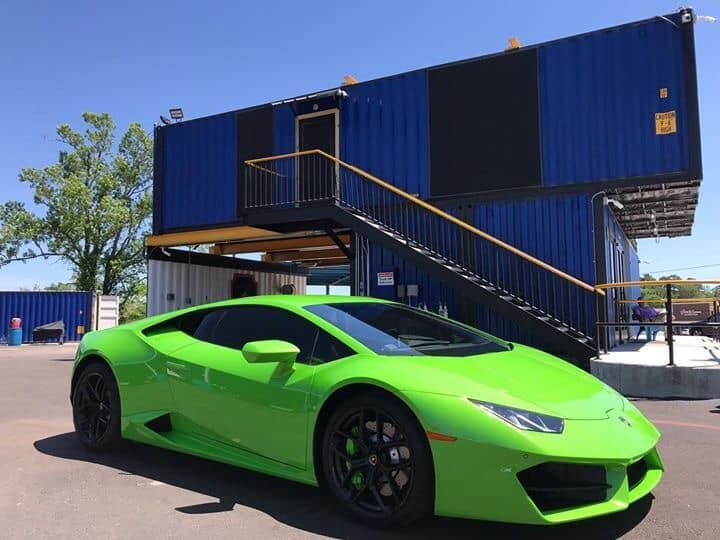 A green lamborghini huracan is parked in front of a blue building.