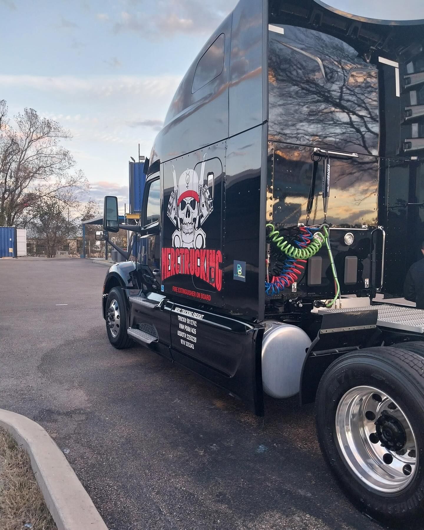 A black semi truck is parked in a parking lot.