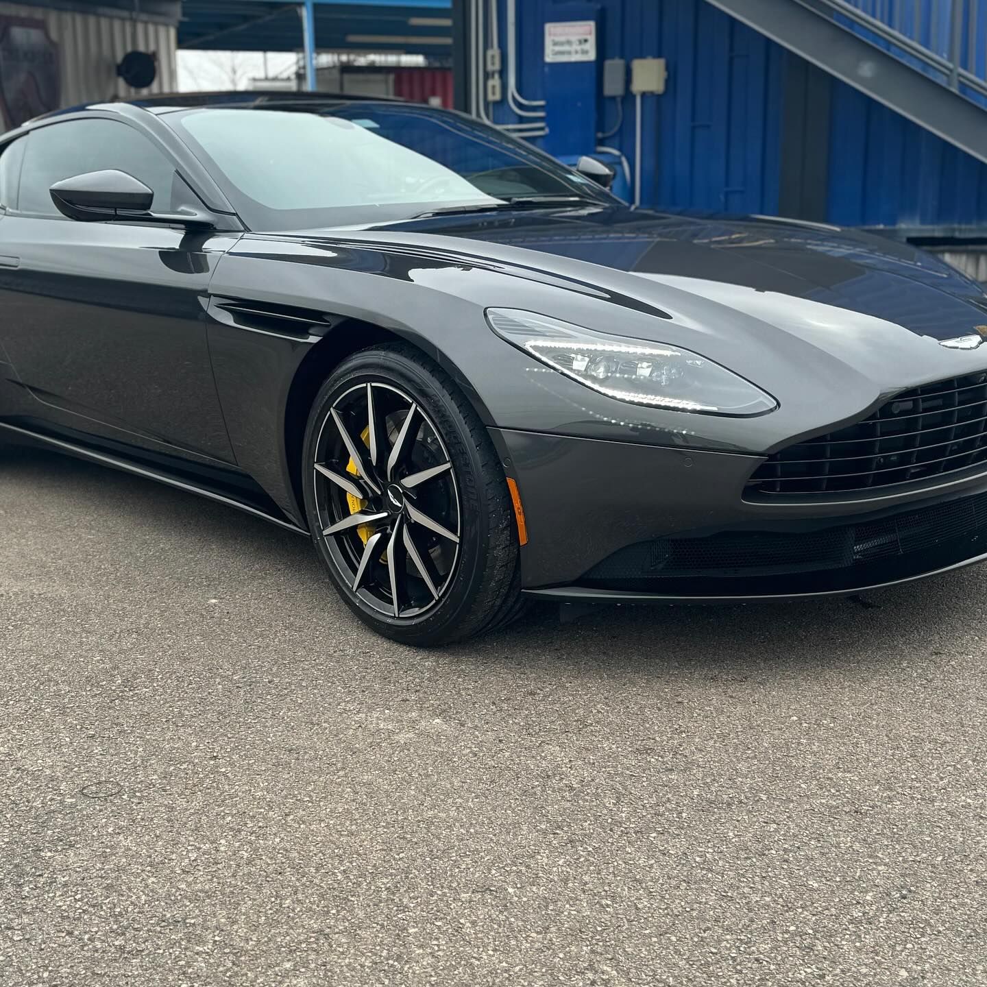 A black sports car is parked in front of a blue building.