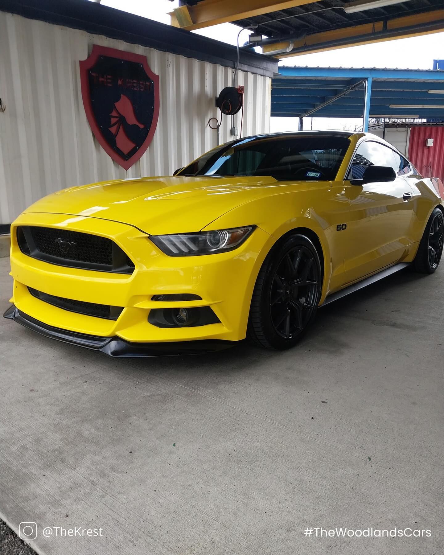 A yellow ford mustang is parked in front of a building.