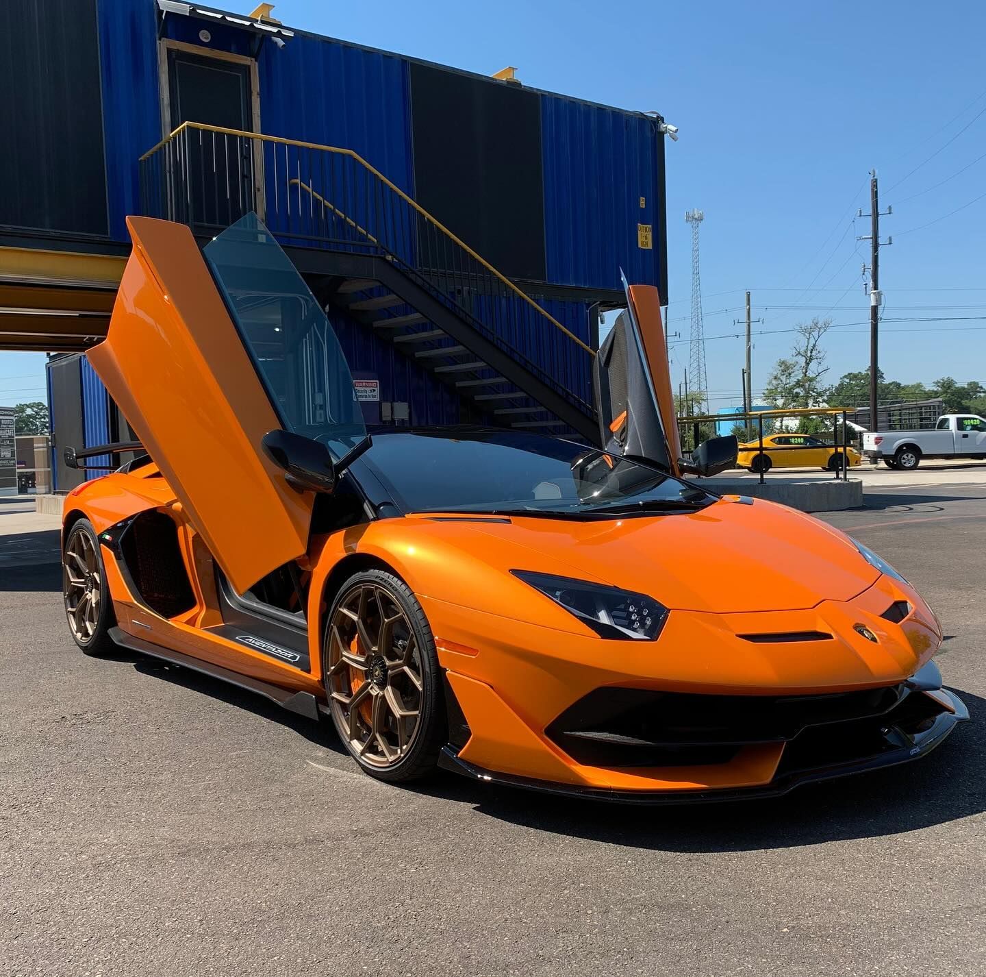 An orange lamborghini aventador is parked in front of a blue building