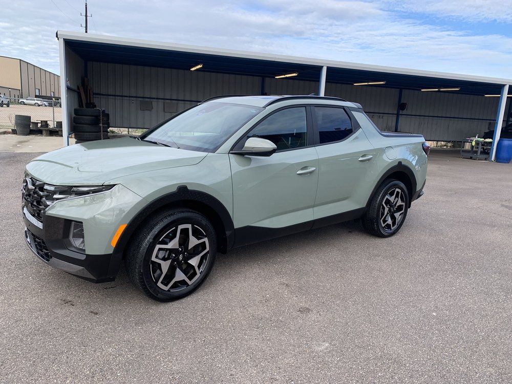 A green pickup truck is parked in front of a building.