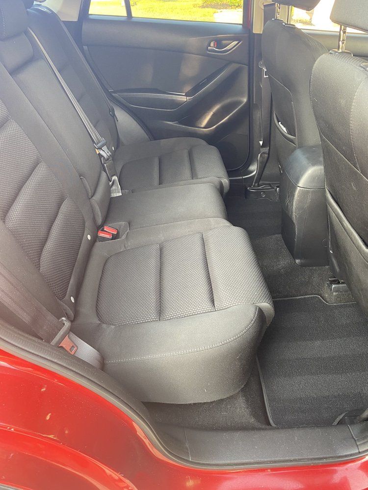The back seat of a red car with black seats.