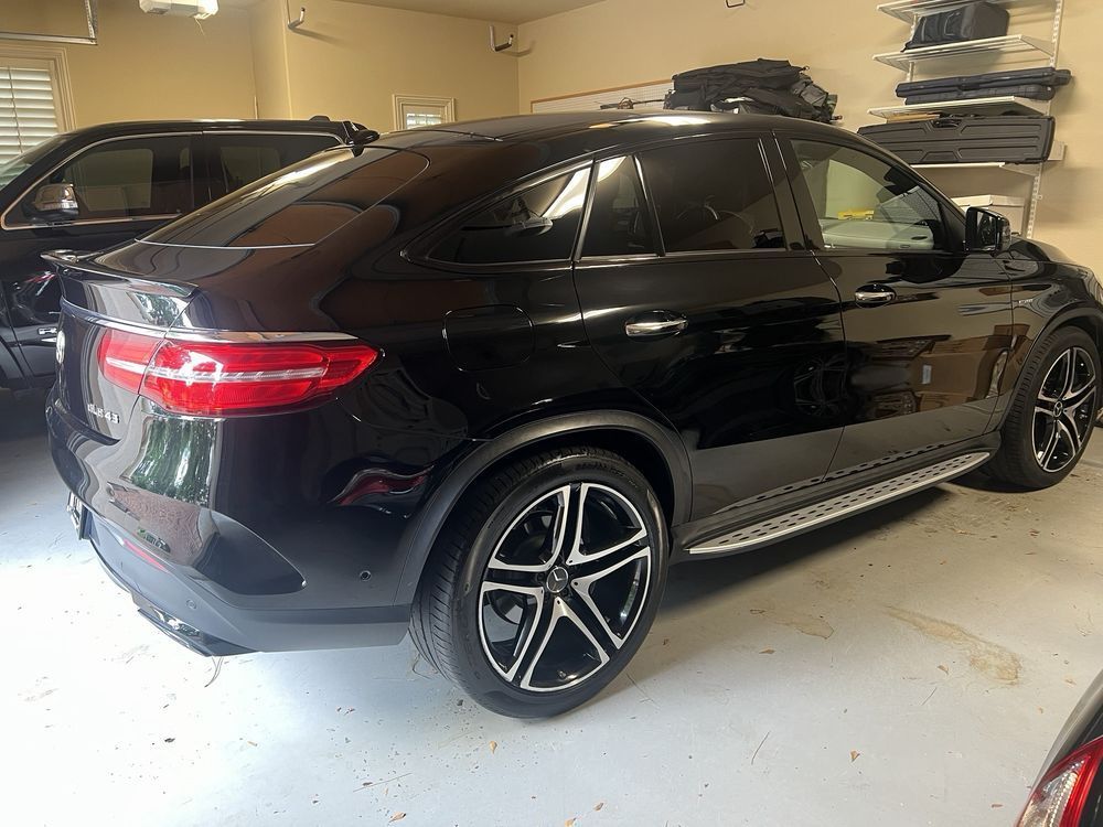 A black suv is parked in a garage next to a black suv.