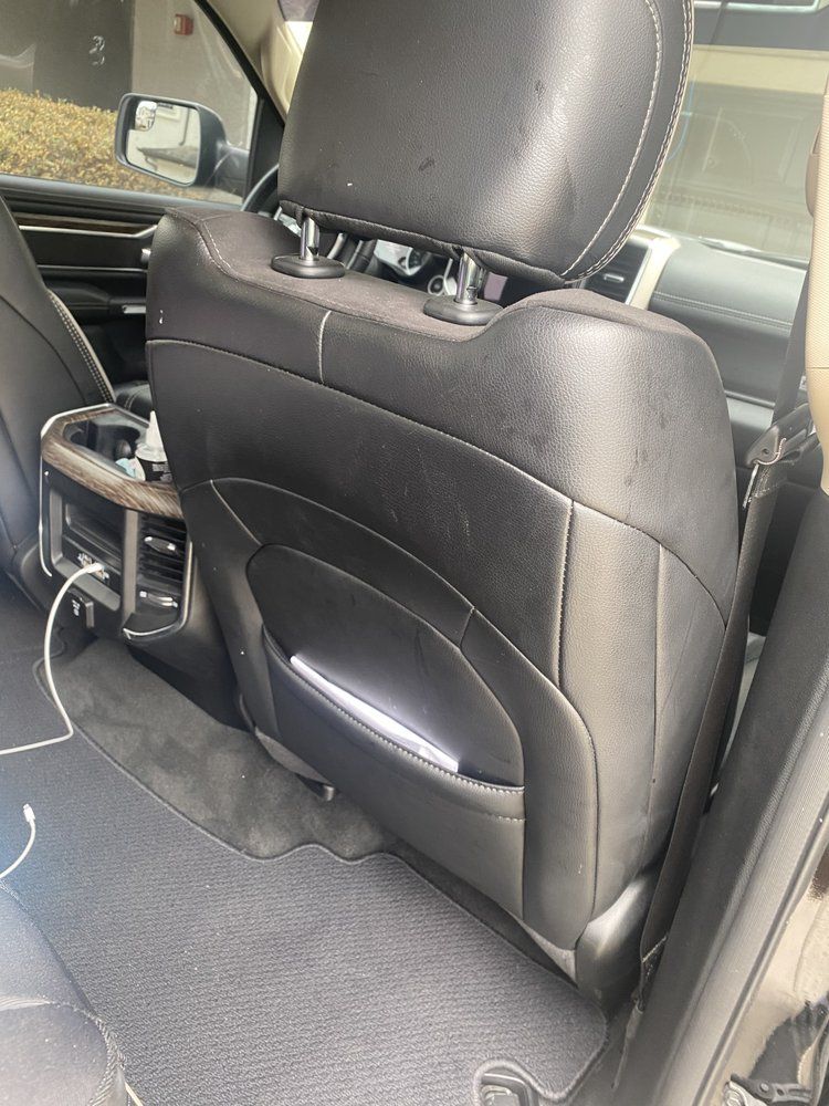 The back seat of a car with a phone plugged into it.