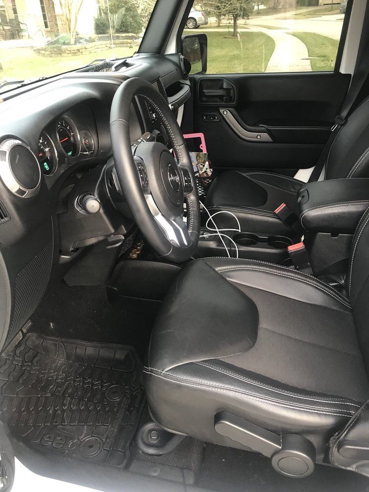 The interior of a jeep wrangler with black seats and a steering wheel.