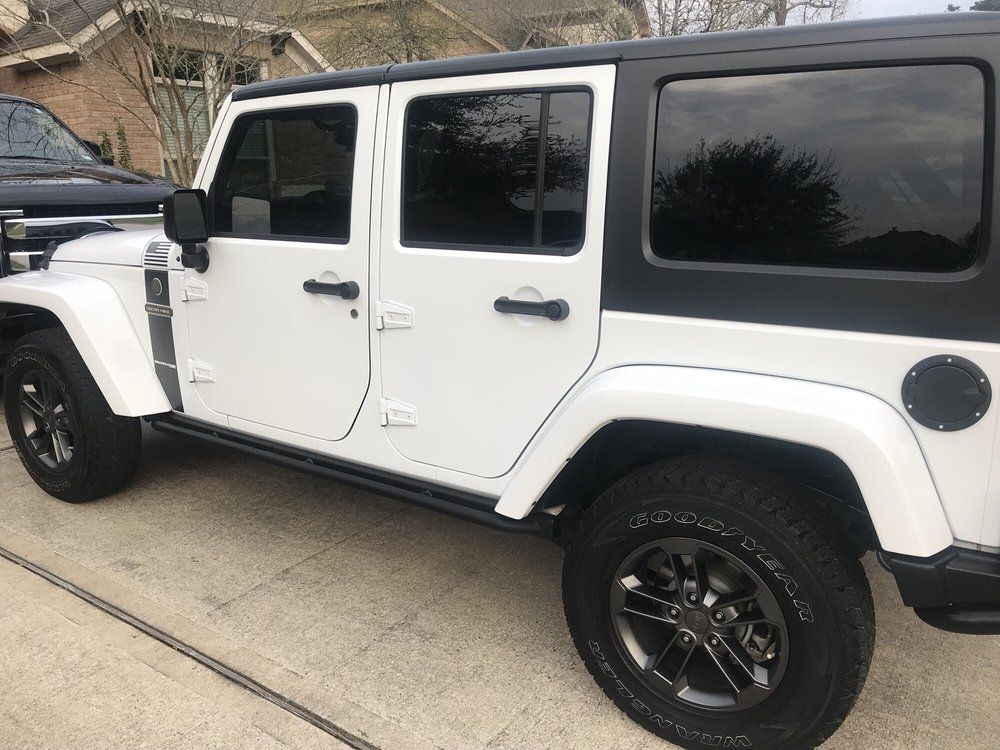 A white jeep is parked in a driveway in front of a house.