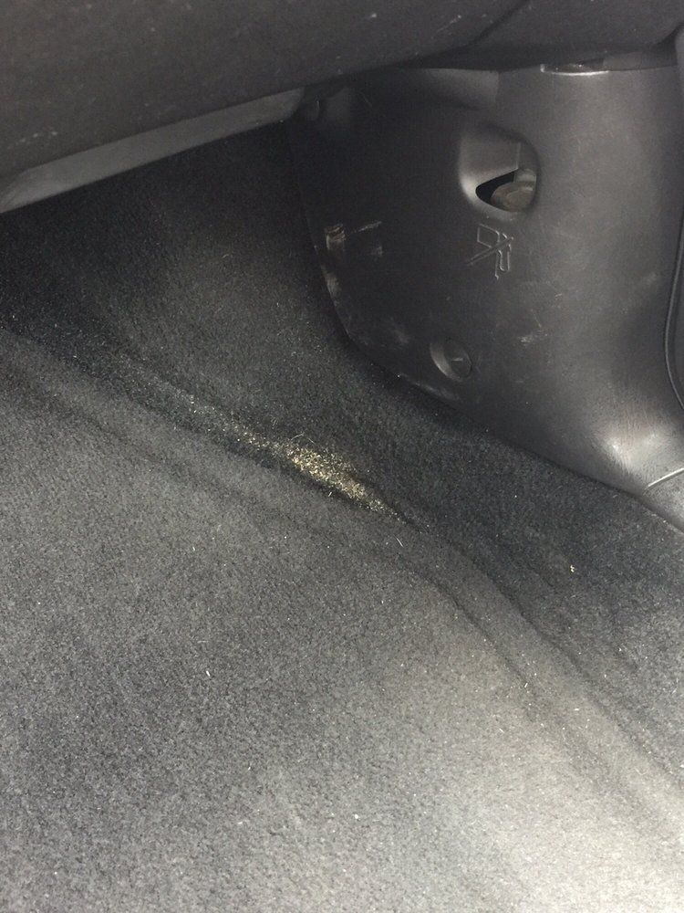 A close up of a black carpeted floor in a car.