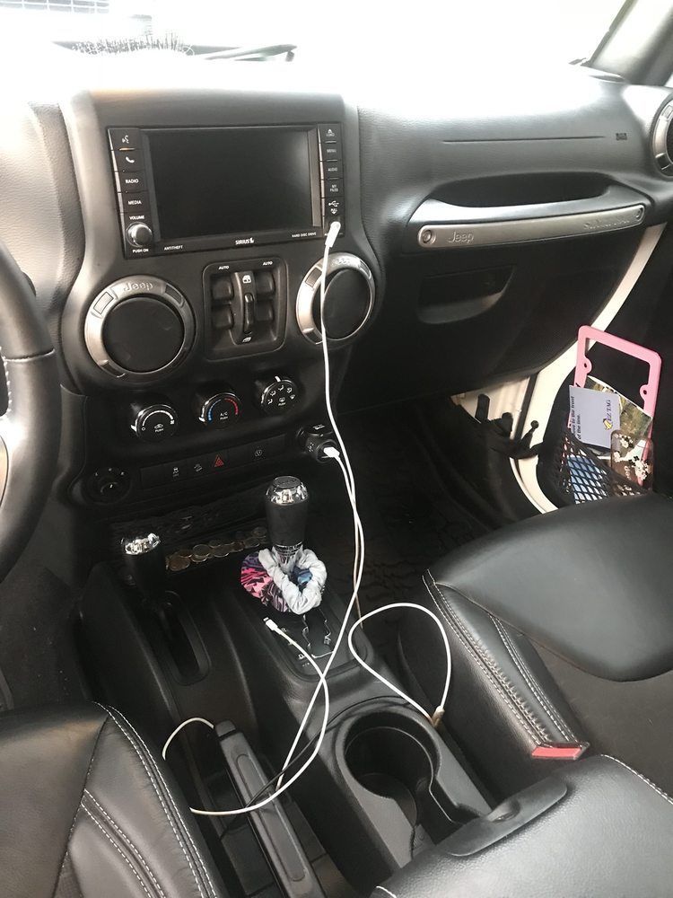 The interior of a jeep wrangler with headphones plugged into the radio.