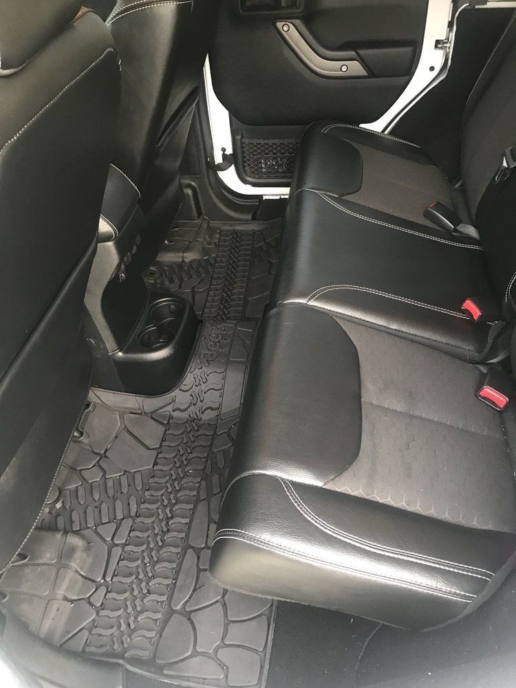 The back seat of a jeep wrangler with a rubber mat on the floor.
