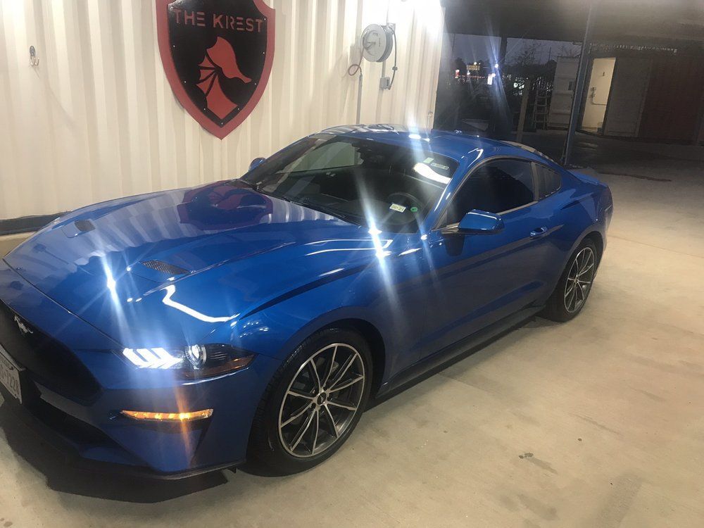 A blue ford mustang is parked in a garage.