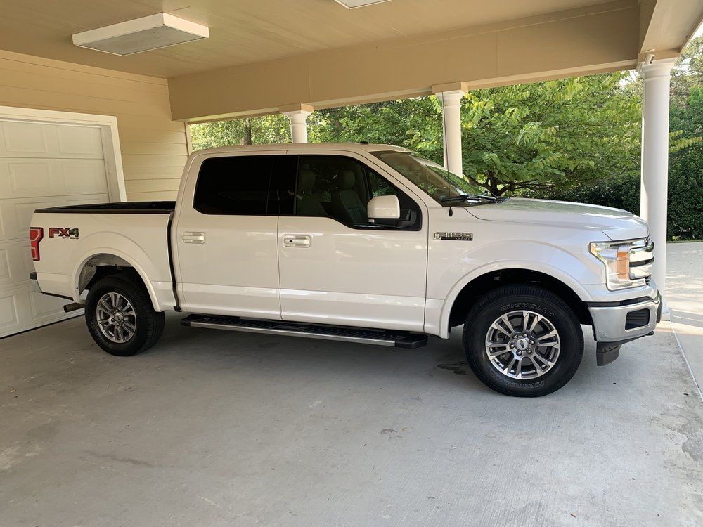 A white ford f150 truck is parked in a garage.