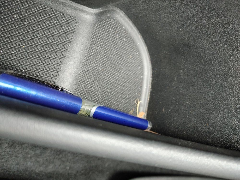 A blue pen is sitting on a black surface.