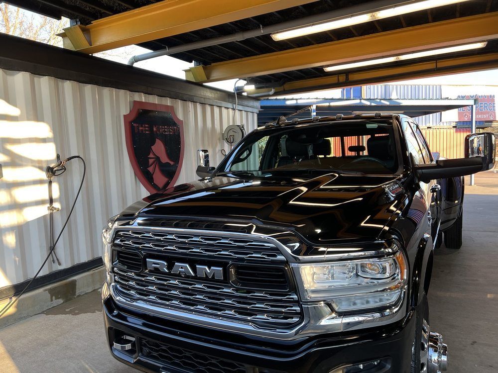 A black ram truck is parked under a covered area.