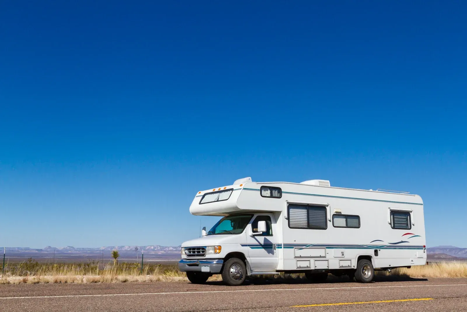 A white rv is parked on the side of the road.