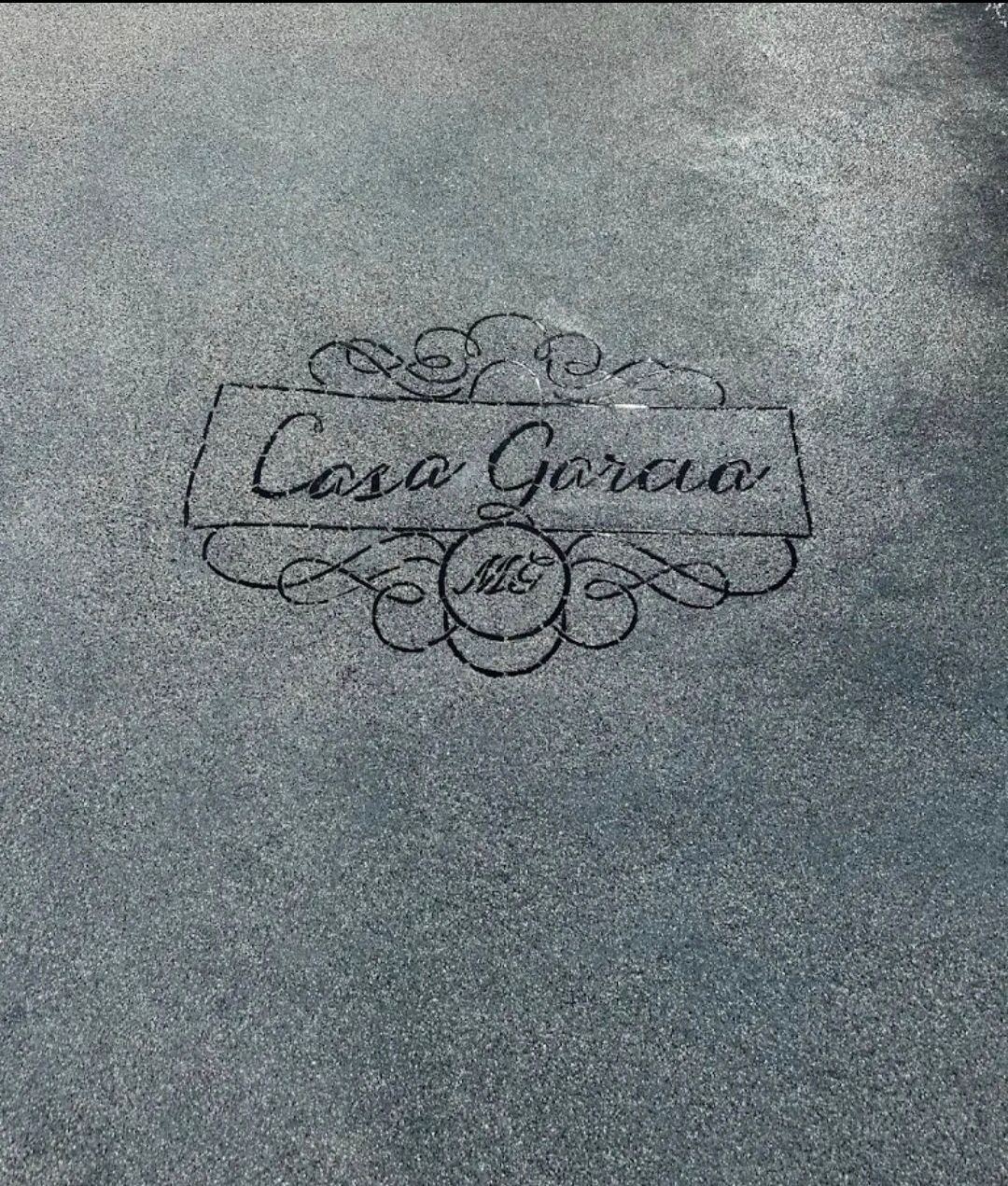 Casa Garcia logo etched in asphalt. The logo is a banner with swirling flourishes, with 