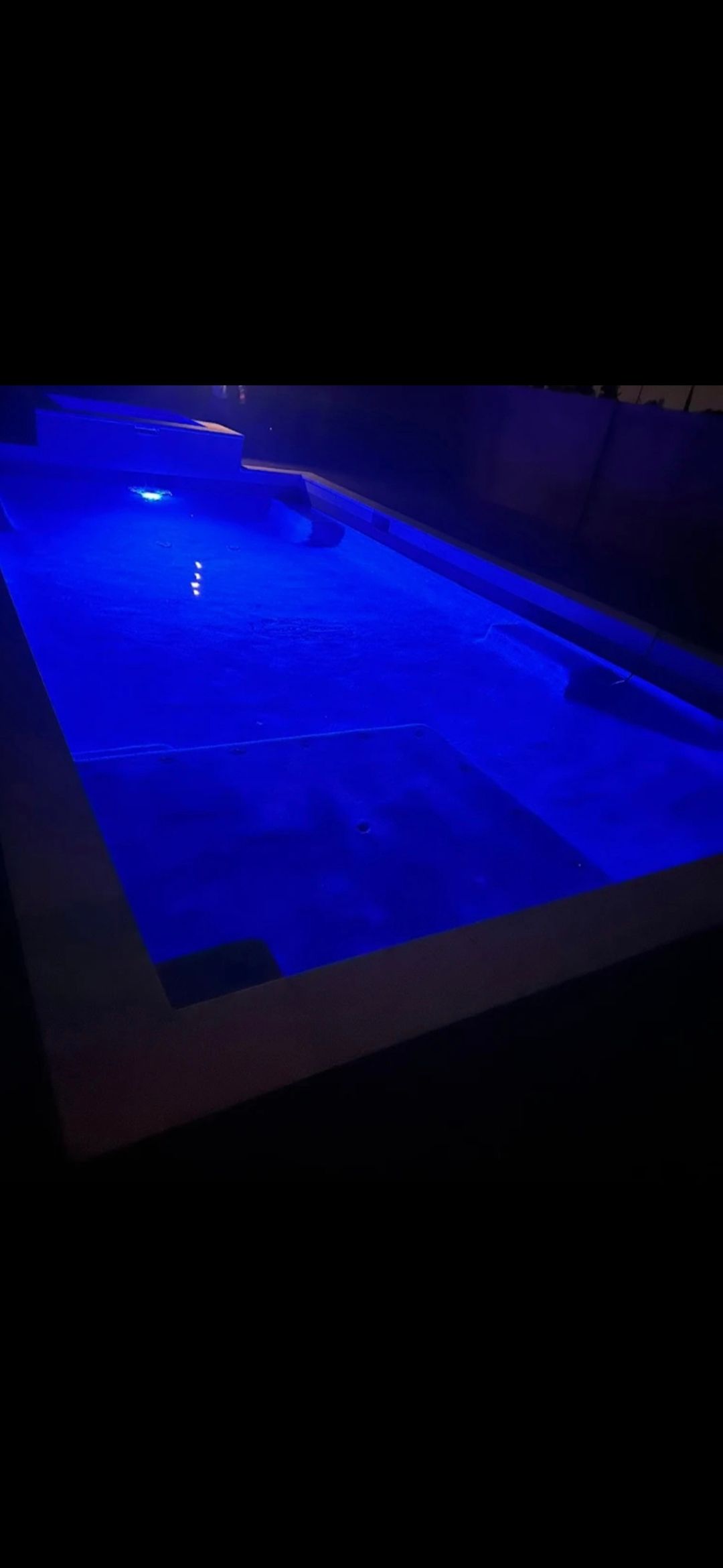 A rectangular pool illuminated with blue light against a dark background.