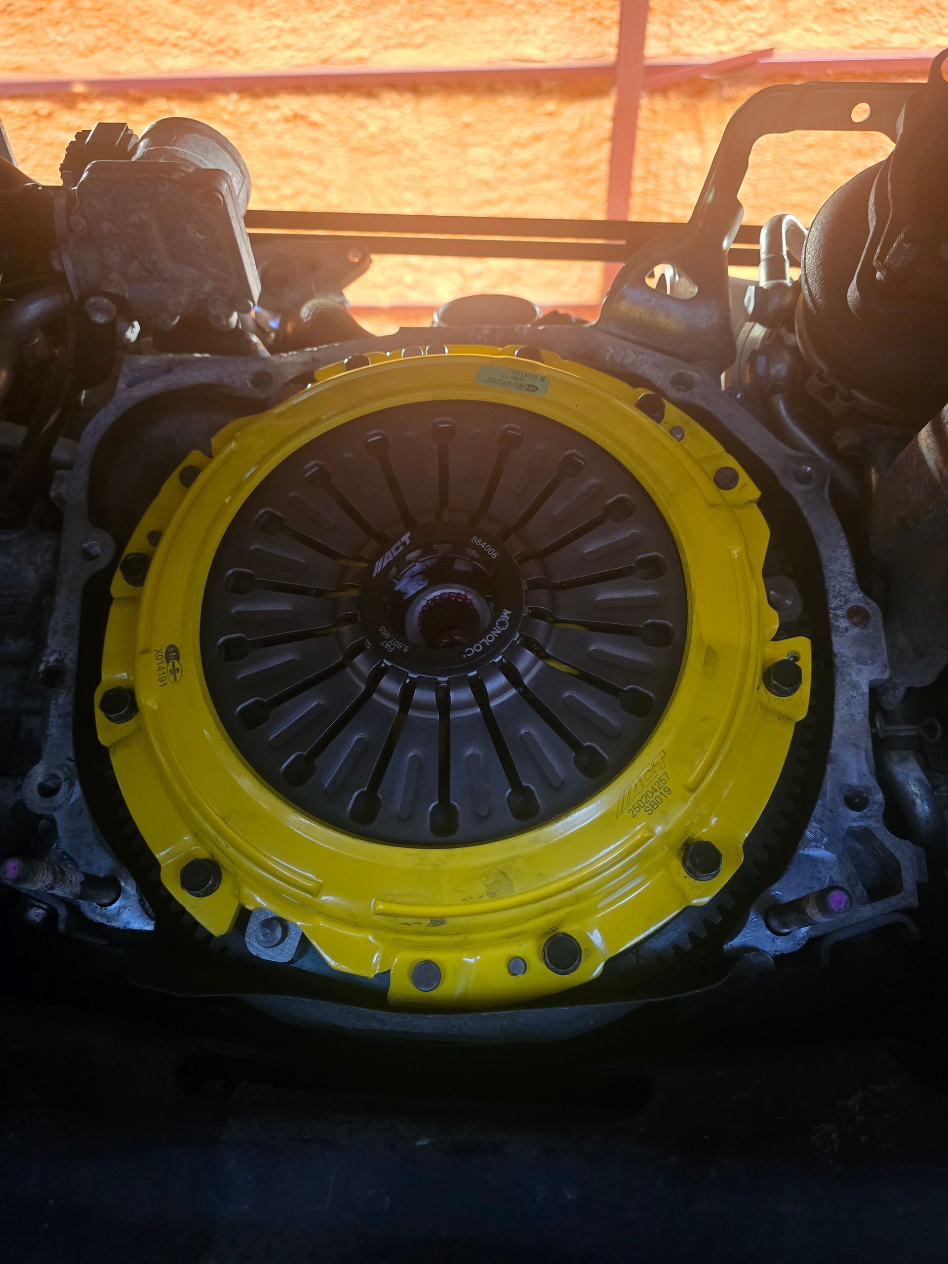 Yellow clutch assembly attached to an engine, viewed from above.