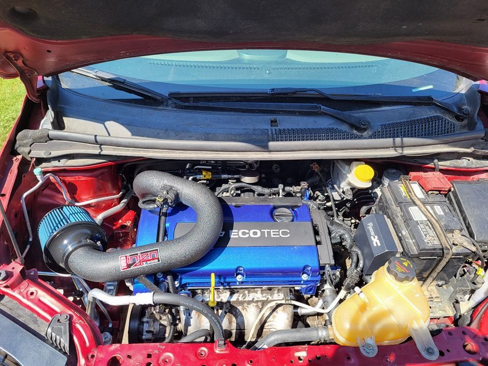 The engine of a red car with the hood open