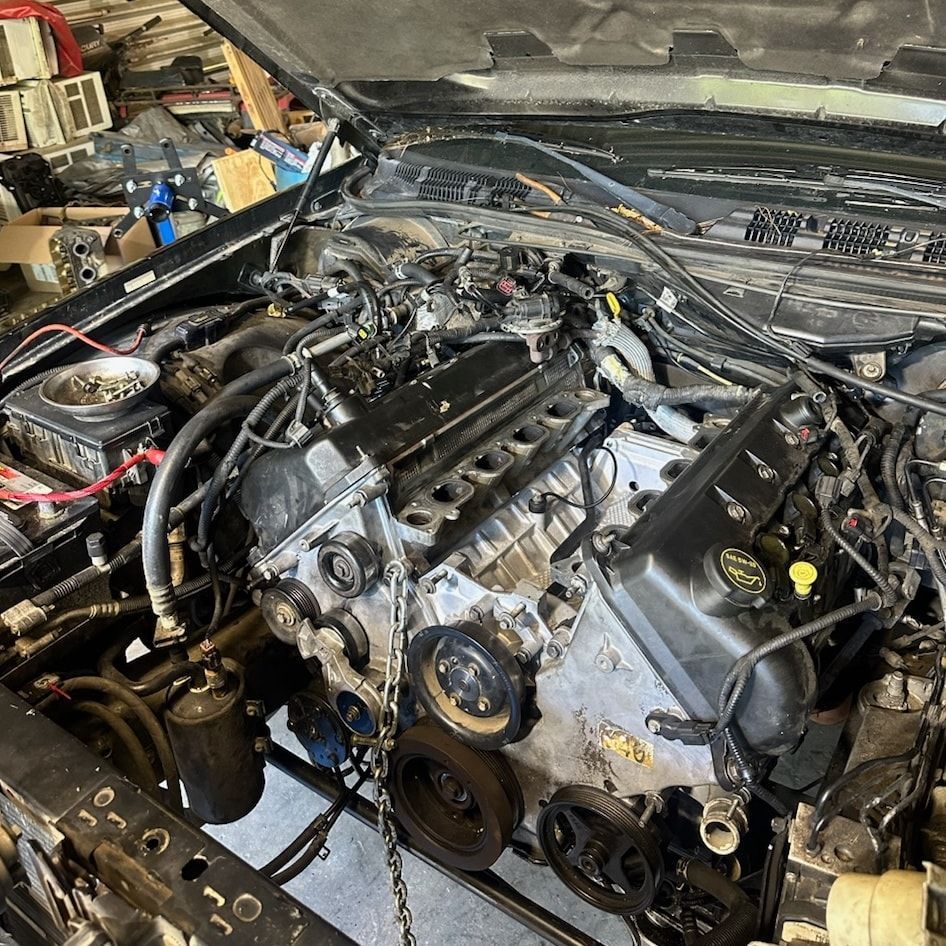 A car engine is being removed from a car in a garage.