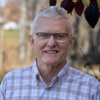 A man wearing glasses and a plaid shirt is smiling for the camera.