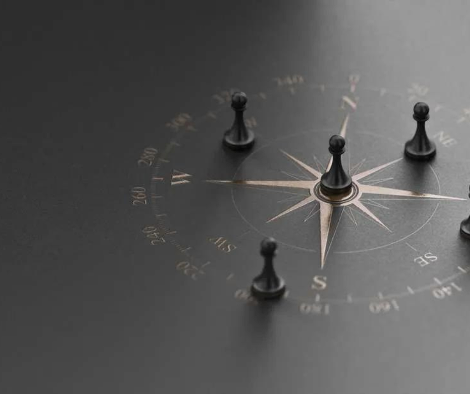 A group of chess pieces are sitting on top of a compass.