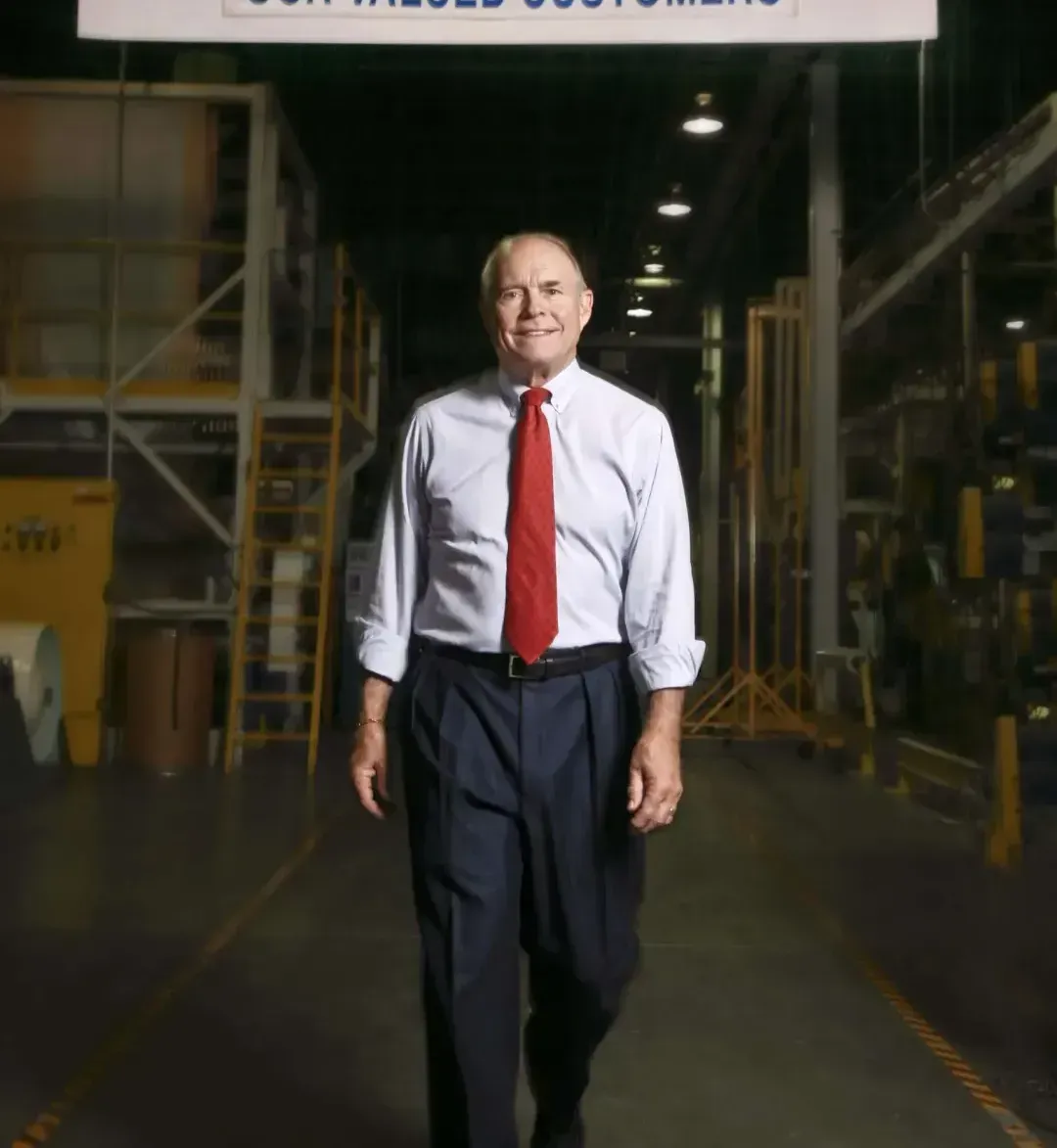 A man in a white shirt and red tie is walking in a warehouse