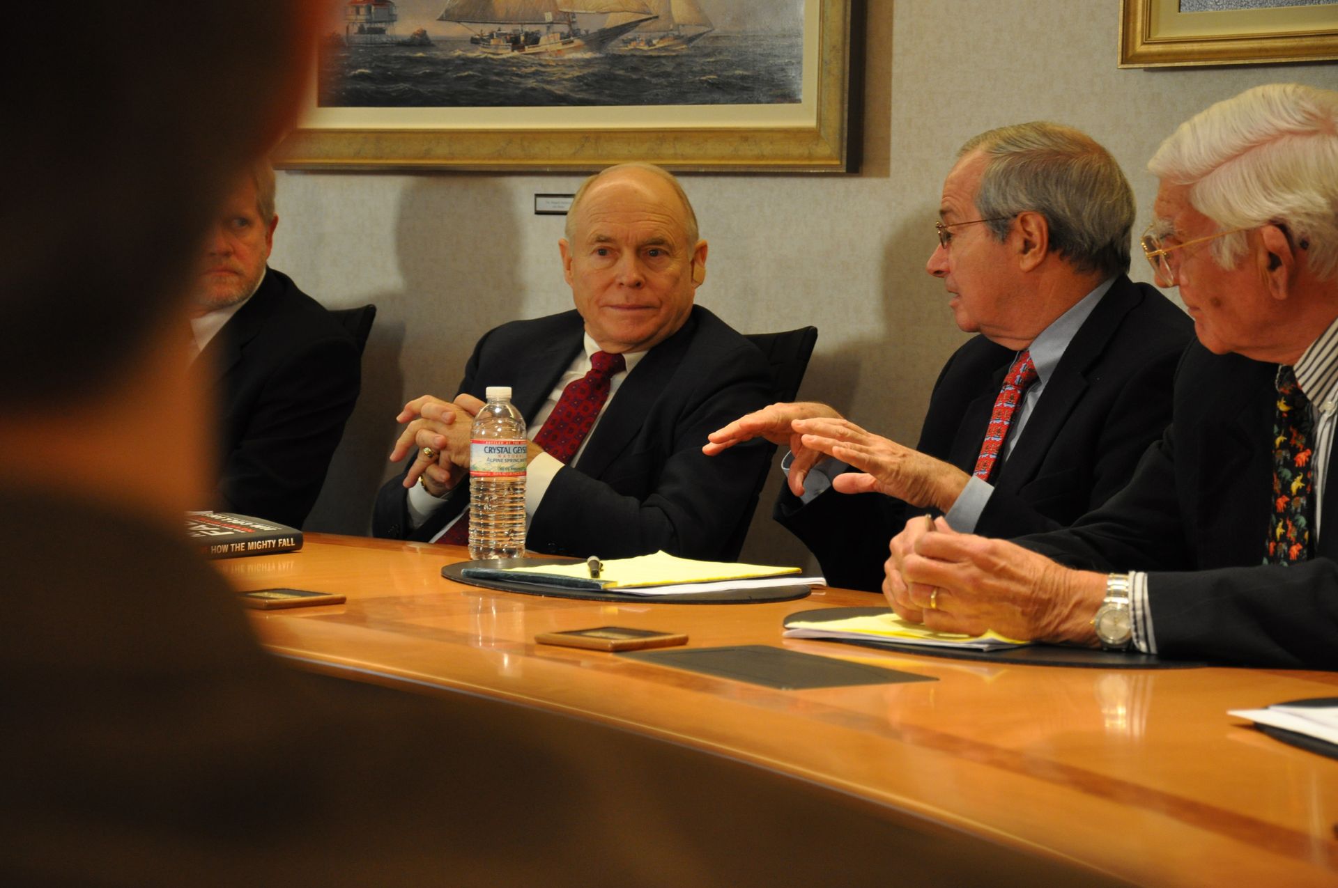 A group of men are sitting around a table with a bottle of water on it