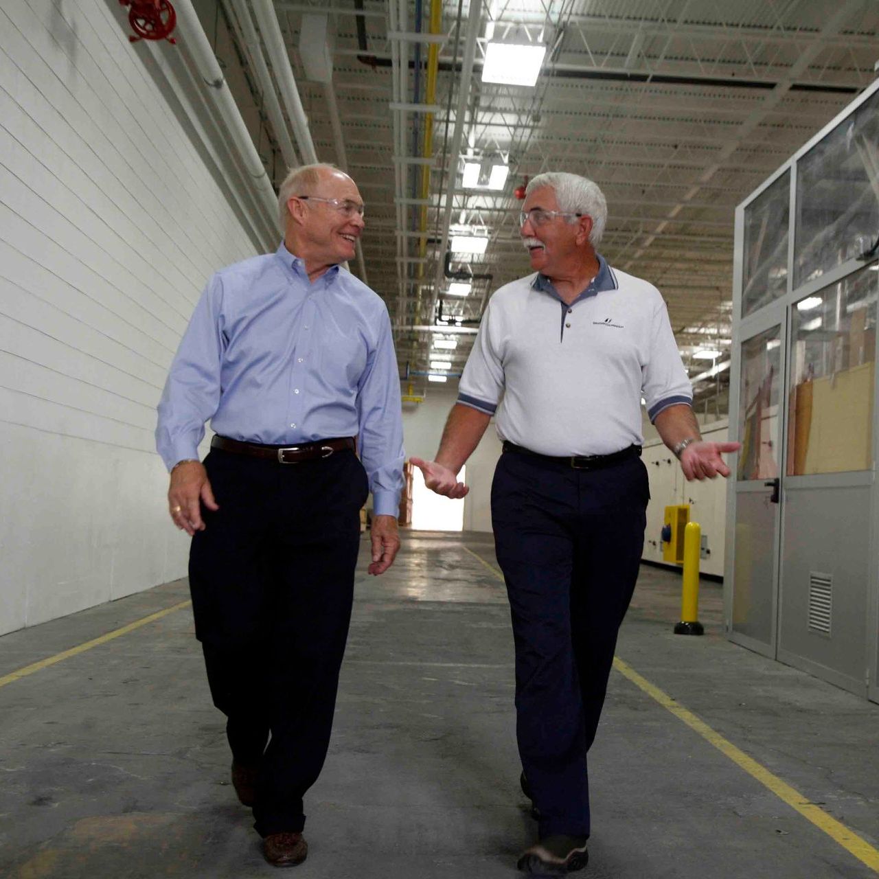 Two men are walking down a hallway holding hands