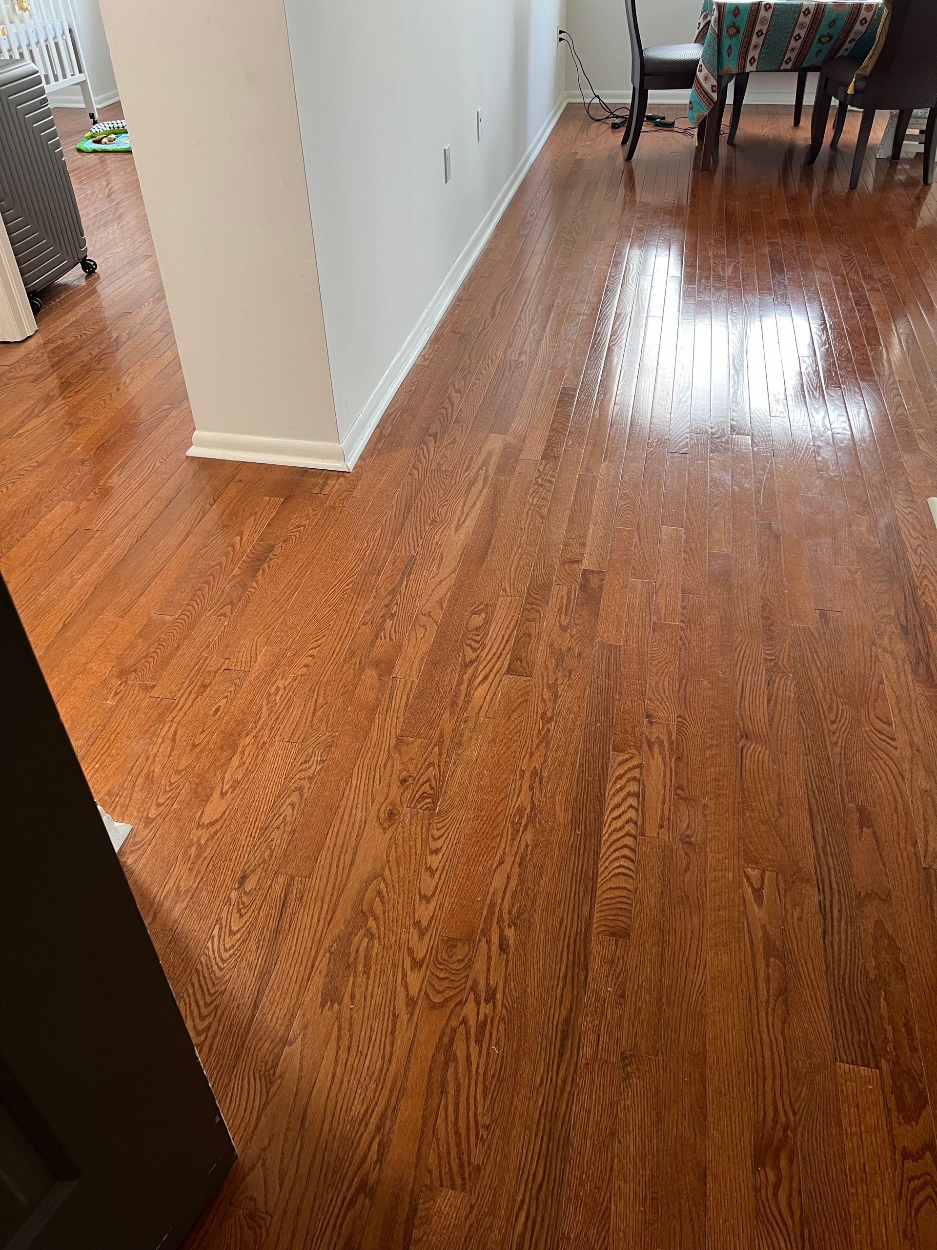 Wood floor with visible water spots, reflecting light, in a home.