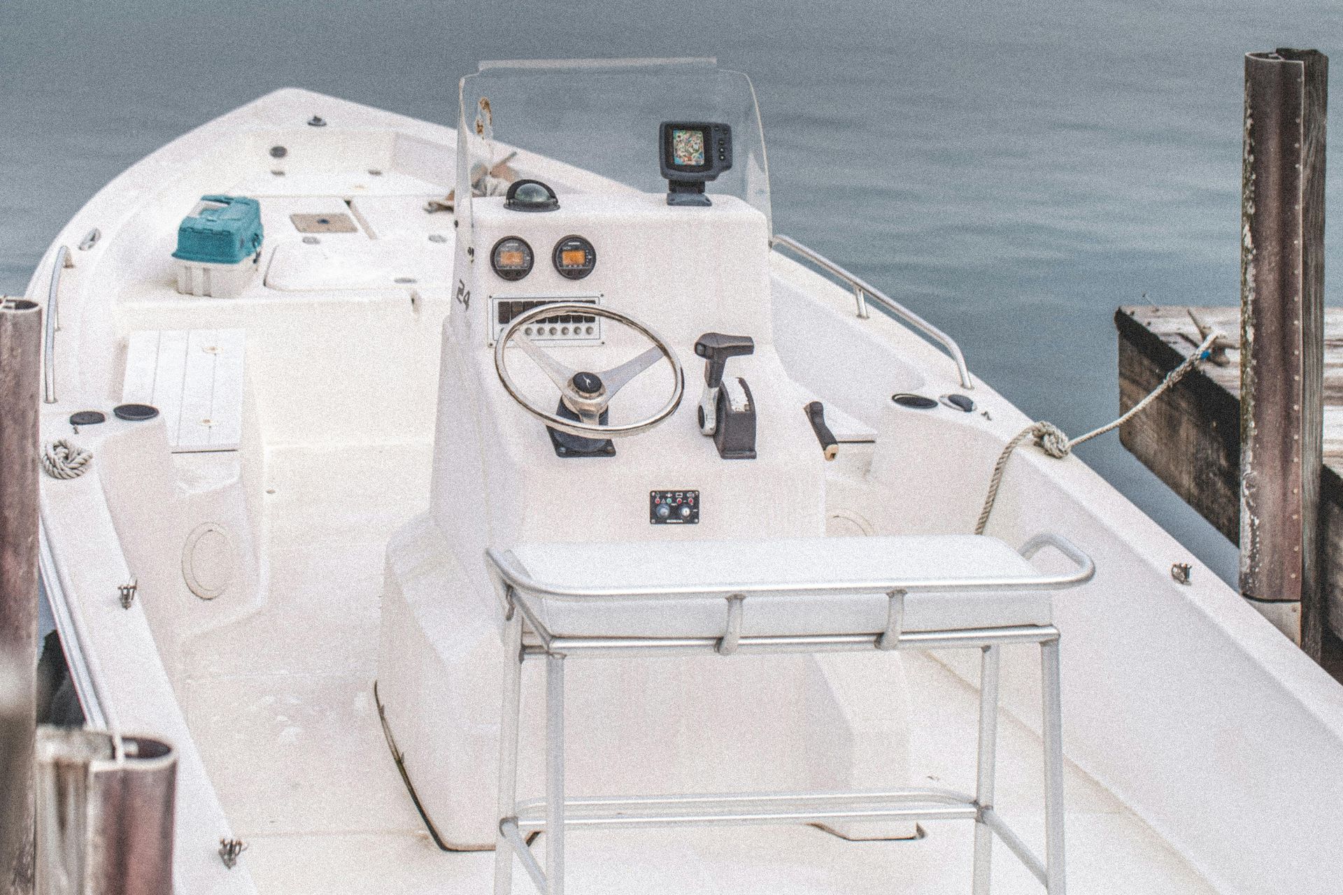 Boat cockpit with white control console, steering wheel, gauges, and a view of the water ahead