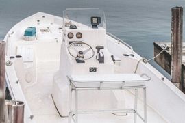 Boat cockpit with white control console, steering wheel, gauges, and a view of the water ahead