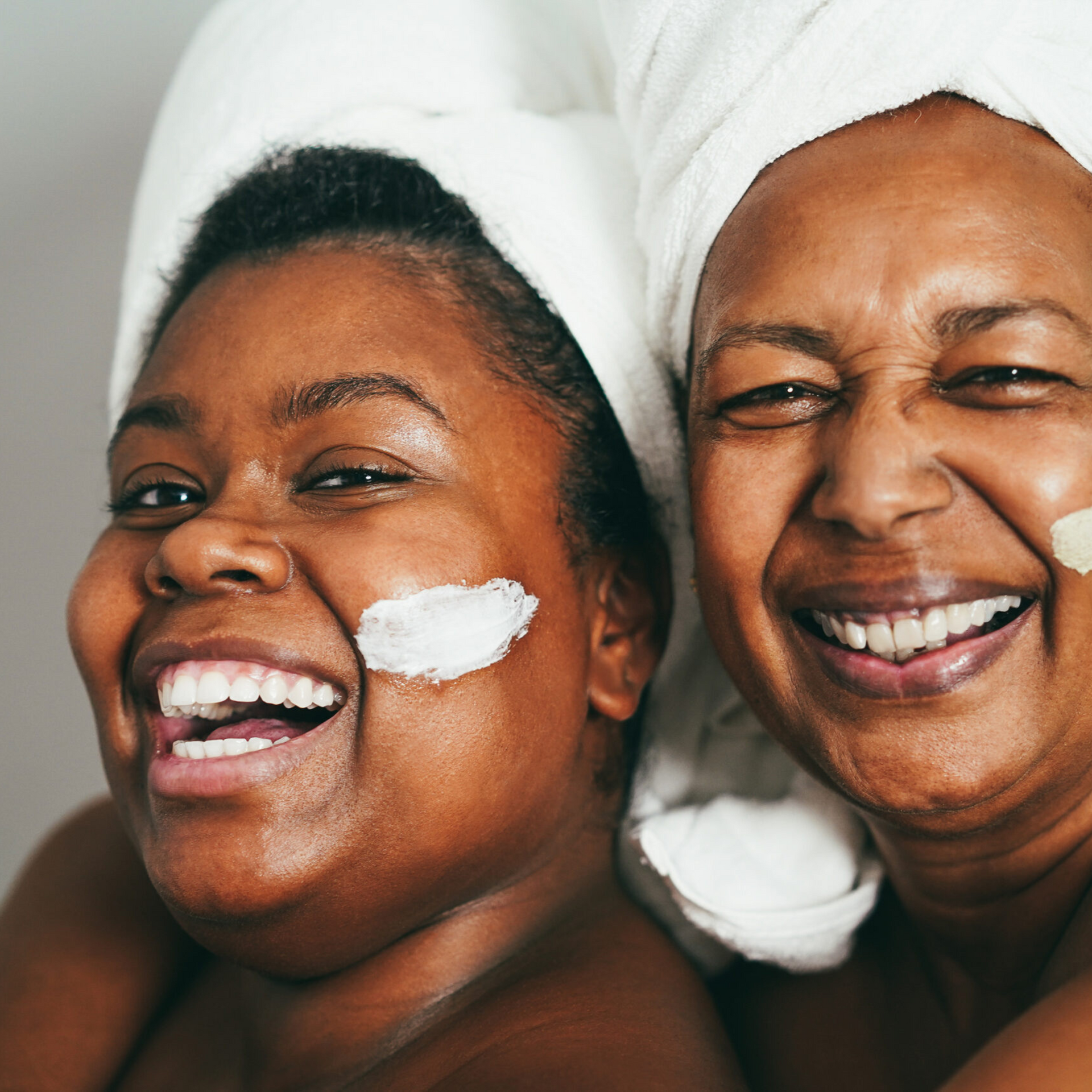 Two women with towels wrapped around their heads are smiling for the camera.